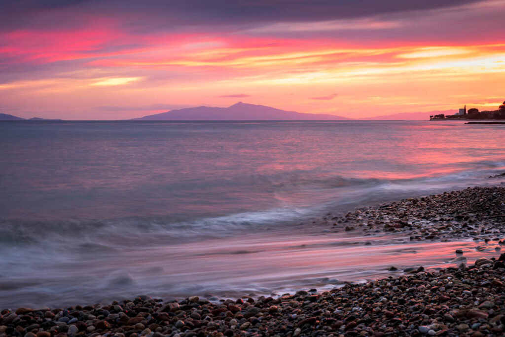 Colorful Sunset over Rocky Beach with Dramatic Clouds