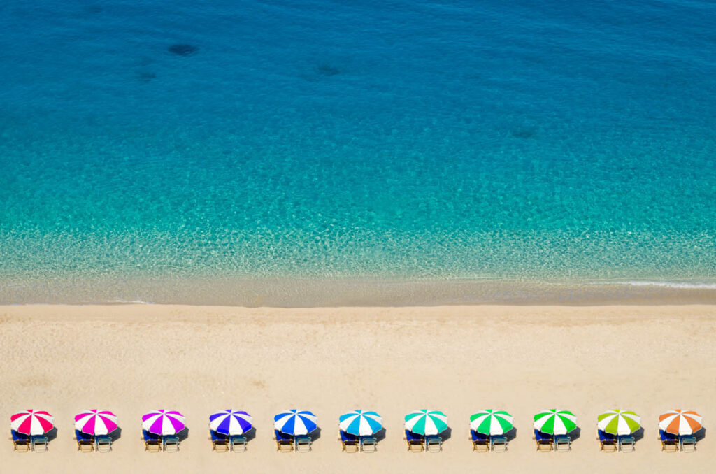 Colorful umbrellas on a golden sand beach and turquoise waters sea